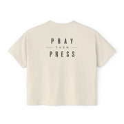 An off-white short-sleeve t-shirt with the text 'PRAY THEN PRESS' printed in black on the chest, displayed against a solid white background.