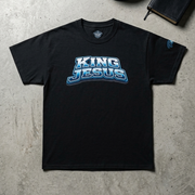 Black t-shirt with 'King Jesus' text, belt, and notebook on a gray surface