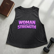 Black tank top with 'Woman of Strength' text on a gray surface with a Bible and dumbbell.
